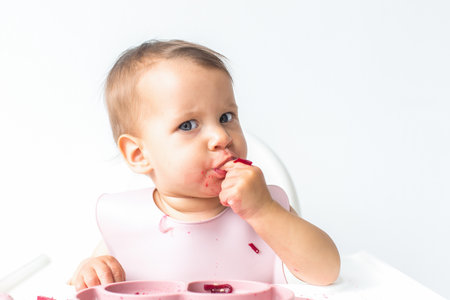 portrait baby cute girl on white background, eats food blw.の写真素材