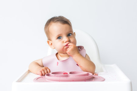 baby little girl 8 months old sits in a high chair and eats complementary foods. , close-up portrait. baby food concept.の写真素材