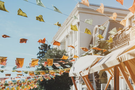sunny warm day in the city, city fair, roofs of wooden pavilions, multi-colored flags against the background of a clear blue skyの写真素材