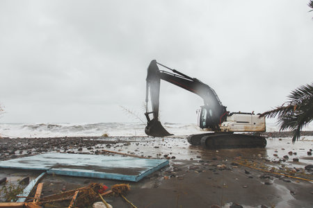 An excavator drives along an embankment destroyed after a storm and hurricane among garbage and debris on the shores of the Black Seaの写真素材