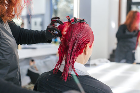 hairdresser colorist dyes a client's hair red in a hair salonの写真素材