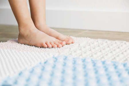 child's feet on an orthopedic mat, exercises for legs orthopedic massage carpet, orthopedic massage puzzle floor mats with colorful details for preventing flatfoot, close up.の写真素材