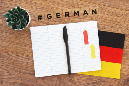 German flag, notebook, pen and inscription hashtag german on a wooden desktop, foreign language learning concept 1の写真素材