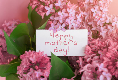 beautiful spring bouquet of lilac flowers and gift cardboard white card with the inscription happy...