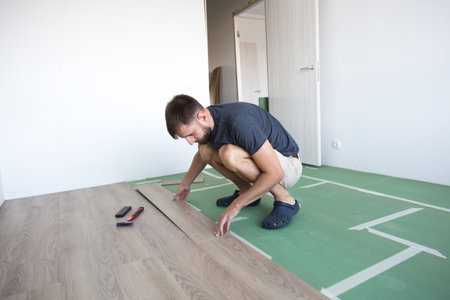 male foreman lays laminate flooring in the room, renovation concept.の写真素材