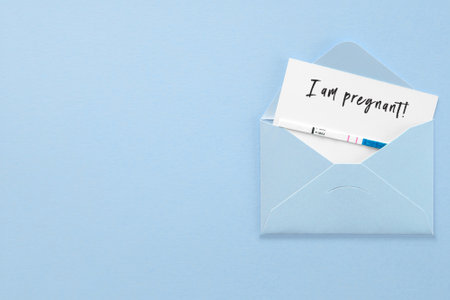 positive pregnancy test in blue envelope on blue background, postcard with description i am pregnant, pregnancy conceptの写真素材