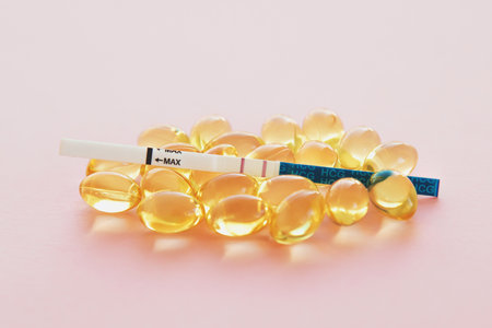 positive pregnancy test and vitamins pills on pink background close up, pregnancy concept.