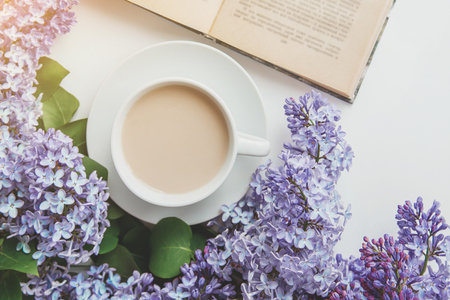 spring composition flat lay white cup of coffee, pink lilac beautiful bouquet of lilacs, old book, concept of spring and comfortの写真素材
