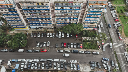 Aerial view of a Soviet-era apartment building and crowded parking lot in Batumi, Georgia, showing everyday urban life with tightly packed cars and residential balconies, concept of city lifeの写真素材