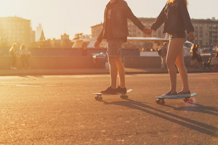 couple in love riding skateboards around the city at sunset, face not visibleの写真素材