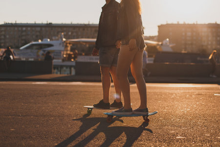 couple in love riding skateboards around the city at sunset, face not visibleの写真素材