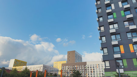 Colorful modern residential buildings with geometric designs under a bright blue sky and fluffy...