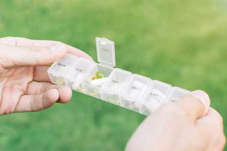 Weekly pill organizer with compartments for each day of the week filled with capsules and tablets...