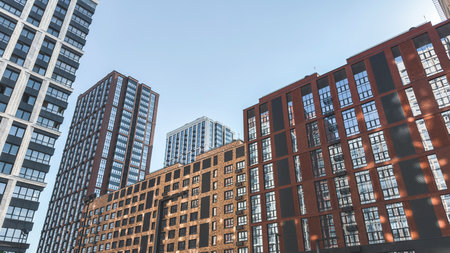 Modern high-rise residential buildings with glass facades and brick elements under clear blue sky, representing contemporary urban architecture, real estate development and city lifestyleの写真素材