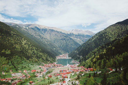 Picturesque view of Uzungol Lake surrounded by lush green mountains and red-roofed houses in Karadeniz region, Turkey. Concept of travel, nature, landscape, tourism, and scenic mountain villageの写真素材