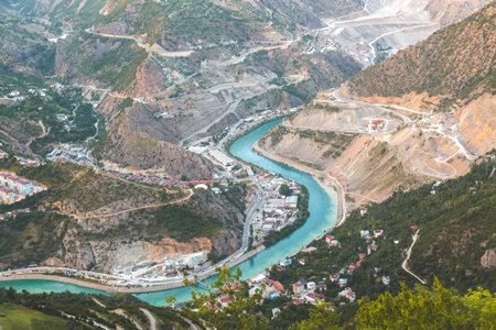 turquoise waters Chorokh River wind through mountainous valley near the city of Artvin, surrounded by steep cliffs, green hills and small settlements, symbolizing harmony of nature human developmentの写真素材