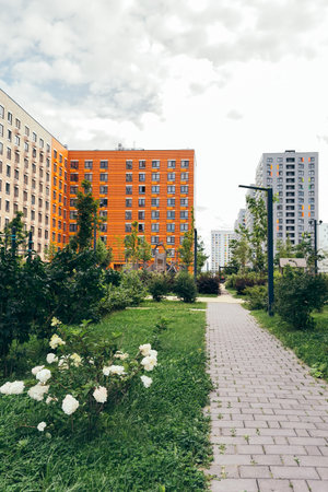 Modern residential courtyard with green laws, flowers, paved walkways surrounded by colorful...