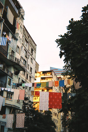 Old residential buildings with balconies and colorful laundry hanging between them in warm evening...