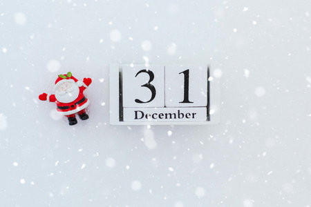 small figure of santa claus on the snow next to wooden calendar with date of December 31, new year concept 1の写真素材
