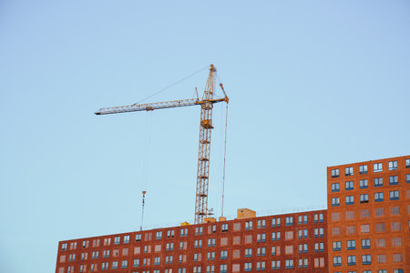 construction of a modern apartment building: crane against blue sky 1の写真素材