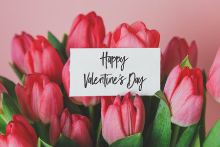 a bouquet of beautiful pink tulips and a white gift card with the inscription Happy Valentine's Dayの写真素材