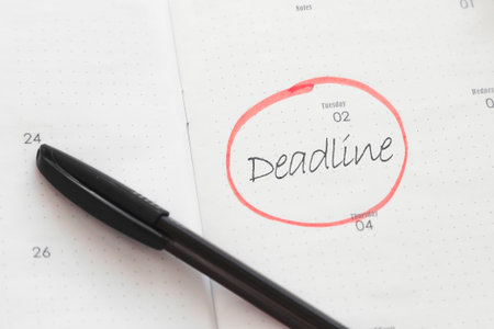 Open planner with the word deadline handwritten and circled in red ink, black pen lying nearby, concept of time management, productivity, project planning and business organizationの写真素材
