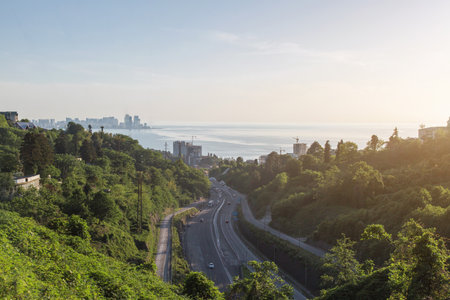 Scenic view of winding road passing above tunnel in Batumi, Georgia, surrounded by lush green hills...
