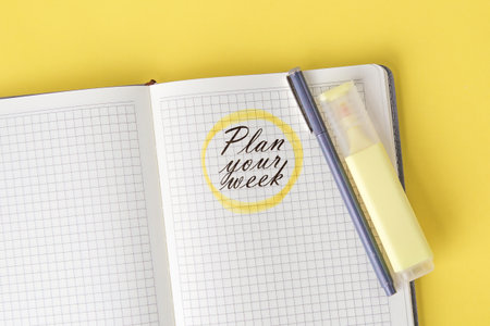 Open notebook with grid pages showing the handwritten phrase Plan your week circled in yellow, with...