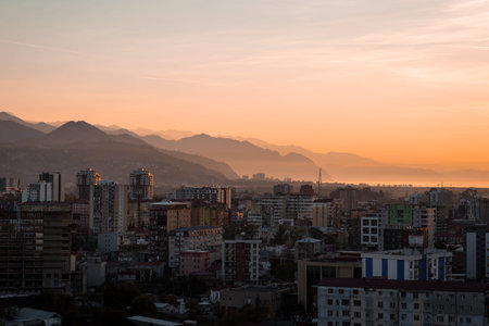 Sunset view over Batumi with silhouettes of Gonio and layered mountain ridges. Warm golden light...