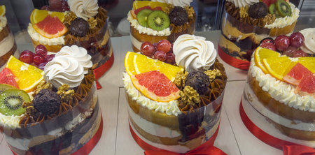 Assorted layered cakes topped with fresh fruits, nuts, whipped cream, and chocolate decorations...