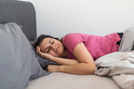 Peaceful woman sleeping comfortably in bed, showing healthy sleep habits, relaxation, and good sleep...
