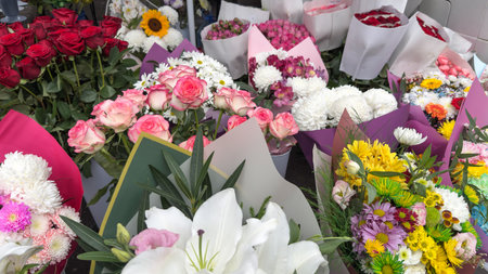 Vibrant mix of fresh flower bouquets featuring roses, lilies, chrysanthemums and daisies arranged in...