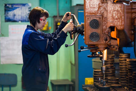 Summer, 2016 - Ussuriysk, Primorsky Krai - Ussuriysky Locomotive Repair Plant. A woman worker is standing behind a machine tool.のeditorial素材