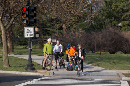 Spring, 2016 - Washington DC, USA - A group of cyclists stand at a traffic light near a road in...