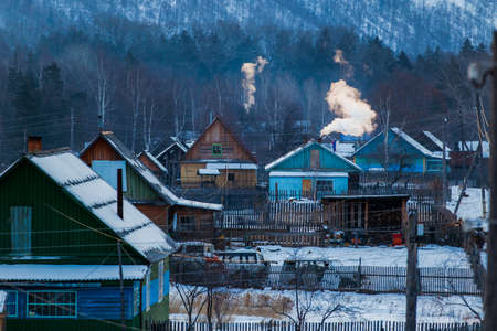 Russian village. Wooden huts with smoke from chimneys in the winter seasonの写真素材