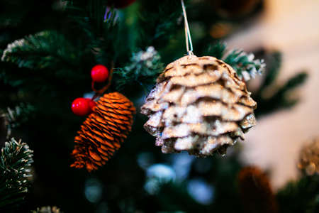 New Year theme. Close-up. A Christmas toy in the form of a pine cone, shot out of focus, hangs on an artificial Christmas treeの写真素材