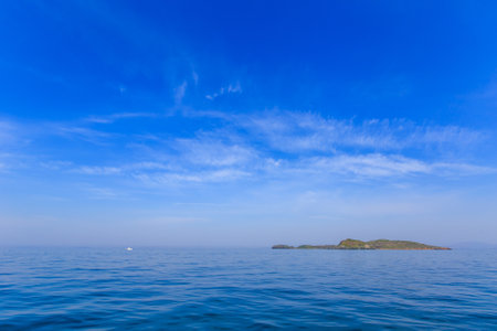 A small uninhabited green island in the middle of a calm blue sea and blue sky. Beautiful relaxation backgroundの写真素材
