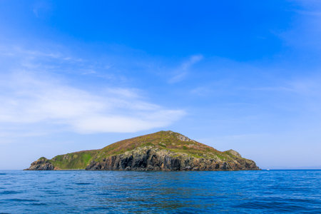 A small uninhabited green island in the middle of a calm blue sea and blue sky. Beautiful relaxation backgroundの写真素材