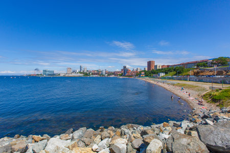 Undeveloped beach in the center of Vladivostok against the backdrop of residential townhouses and the blue seaの写真素材