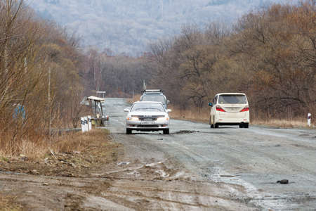 Primorsky Krai, Russia - 2016, autumn - A car drives along a bad, dead road among tall trees....