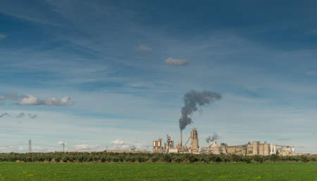 Green Field And Plantation And Factory With Dark Smoke Coming Out Of Chimney In Summer Day With...