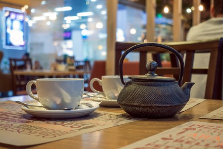 Cafe Table With Tea Kettle And White Cup Interior Shot With Blurry Backgroundの写真素材