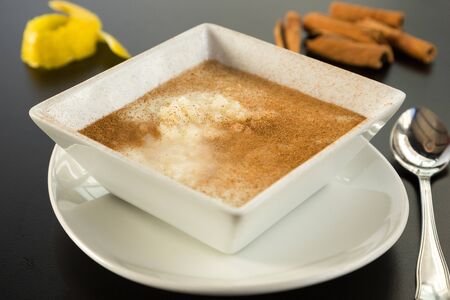 Rice pudding dessert in a bowl with cinnamon on topの写真素材