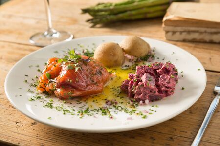 marinated salmon with beet garnish, herbs on top and olive oilの写真素材