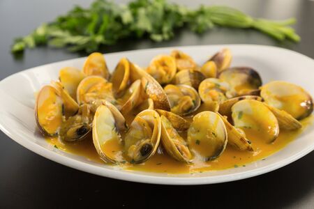 Clams cooked in sauce on a plate on a tableの写真素材
