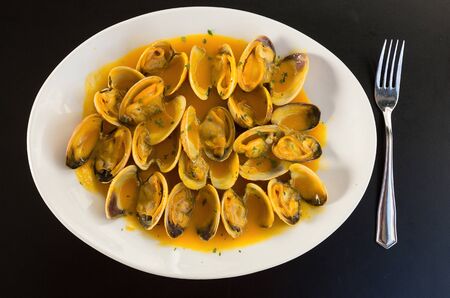 Clams cooked in sauce on a plate on a tableの写真素材