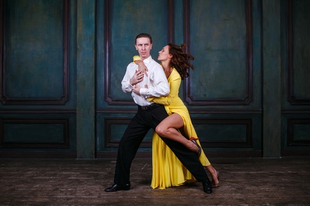 Young pretty woman in yellow dress and man dance tango