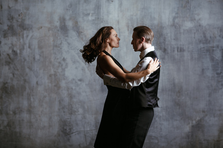 Young pretty woman in black dress and man dance tangoの写真素材