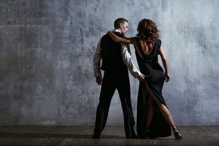 Young pretty woman in black dress and man dance tangoの写真素材