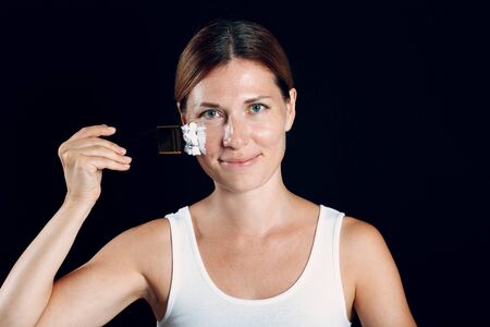 Young woman applying make-up, paints face with painting brush and makeup. How not to do make up concept.の写真素材